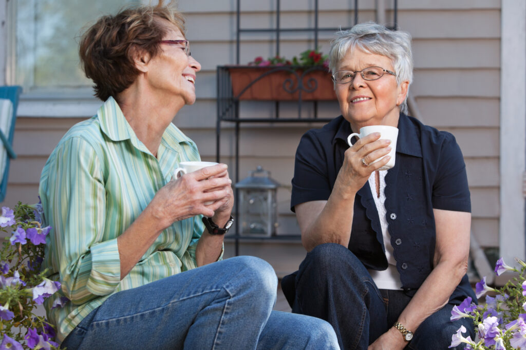 Två äldre damer som dricker kaffe på en terass.